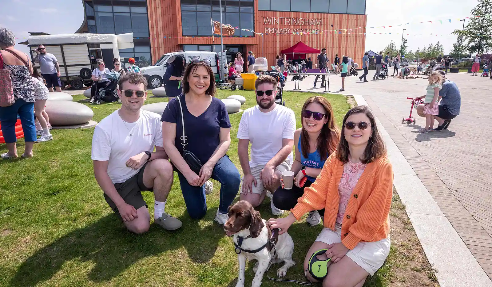 Group of people sitting on the grass in front of Wintringham Primary Academy 